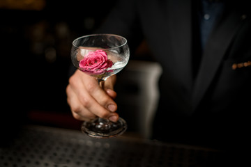 Close-up of bartender holding cocktail with flower