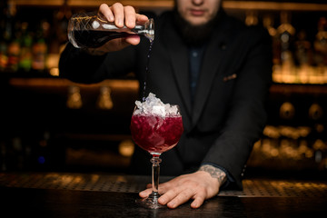 Bartender pours alcohol cocktail in glass with ice