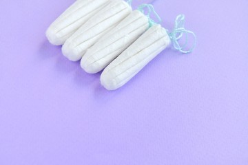 Cotton Hygienic tampons for women period days with selective focus on blurred purple background with empty space for text. Personal protection tampon for menstruated period. Females healthcare 