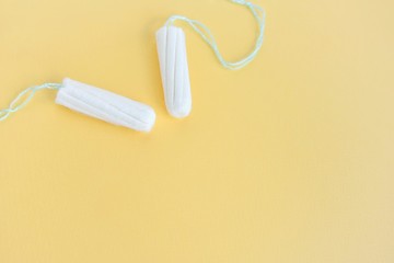 Two cotton tampons for women monthly menstruation with selective focus on blurred yellow...