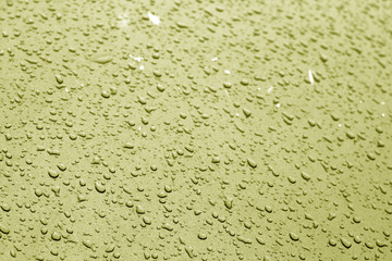 Water drops on car surface in yellow tone.