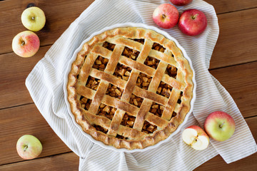 food, culinary and baking concept - apple pie and kitchen towel on wooden table