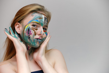 Concept art photo portrait of a beautiful smiling girl woman with red hair with a pattern on her face on a light gray background. Shows emotions. Made in a studio.