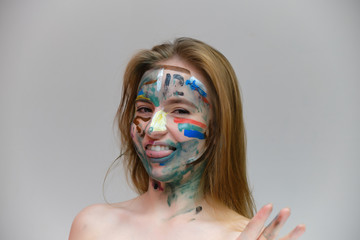 Concept art photo portrait of a beautiful smiling girl woman with red hair with a pattern on her face on a light gray background. Shows emotions. Made in a studio.