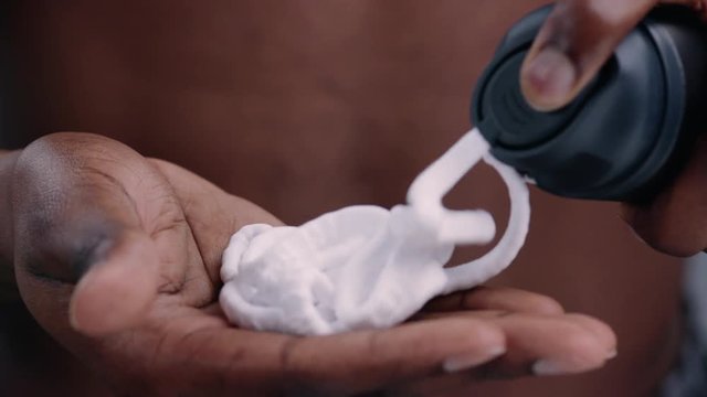 Close-up of black man's hands pouring shaving cream on hands ready to apply on face and shave.