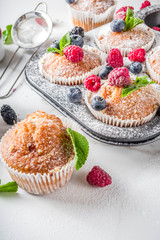 Homemade vanilla muffins or cupcakes with fresh berries on  white marble background