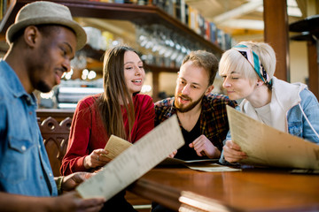 leisure, people and holidays concept - smiling young people in casual clothes reading menu at restaurant