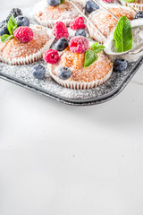 Homemade vanilla muffins or cupcakes with fresh berries on  white marble background