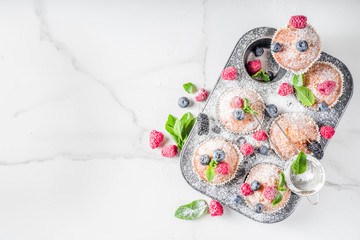Homemade vanilla muffins or cupcakes with fresh berries on  white marble background