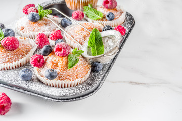 Homemade vanilla muffins or cupcakes with fresh berries on  white marble background