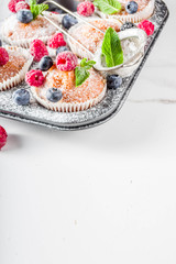 Homemade vanilla muffins or cupcakes with fresh berries on  white marble background