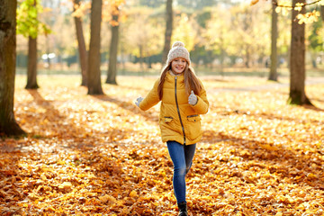 childhood, season and people concept - happy girl running in autumn park
