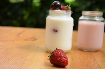 Healthy breakfast - granola, strawberries, cherry, honeysuckle berry, nuts and yogurt in a bowl. Vegetarian concept food. Top view. pudding or cocktail on the background of green foliage