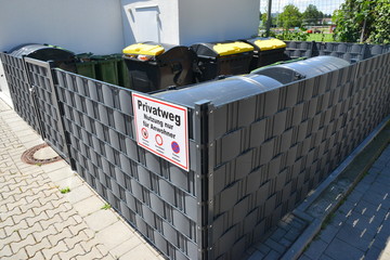 Einfriedung für Abfallsammelbehälter mit Hinweisschild Privatweg an der gepflasterten...