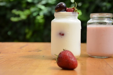 Healthy breakfast - granola, strawberries, cherry, honeysuckle berry, nuts and yogurt in a bowl. Vegetarian concept food. Top view. pudding or cocktail on the background of green foliage