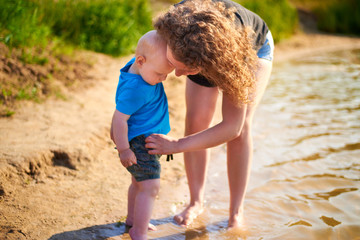 Mom and her son are walking along the river bank on a hot summer day