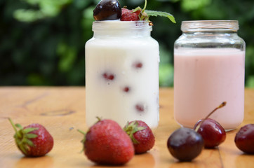 Healthy breakfast - granola, strawberries, cherry, honeysuckle berry, nuts and yogurt in a bowl. Vegetarian concept food. Top view. pudding or cocktail on the background of green foliage