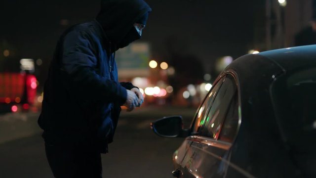 Close up robber man checking shines a flashlight in a car stealing at night crime male thief illegal theft stolen danger burglary bandit secure break safety concept money insurance door slow motion