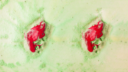 Red bathbomb dissolve in green bubble bath water