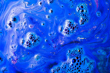 An overhead view of blue bath bomb foam in water