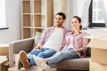 moving, people, repair and real estate concept - happy couple with cardboard boxes sitting on sofa at new home