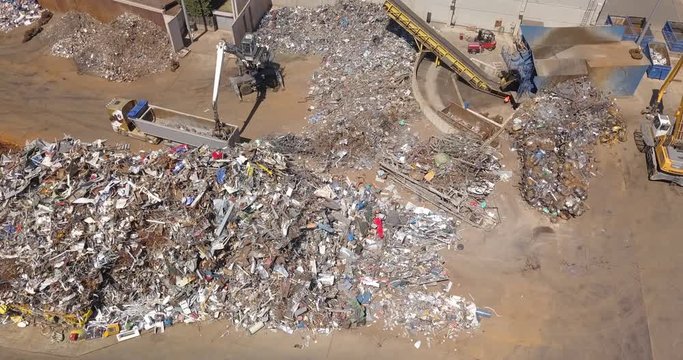 Aerial view of a crane grabbing metal scrap from a dump.