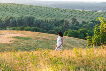 Cute happy romantic beautiful female brunette on the summer green hills