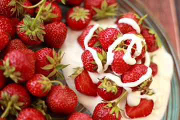 ripe, juicy strawberries with cream in a plate on a wooden table