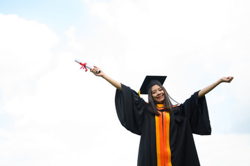 Long haired female students wearing black ruffle dresses expressing joy on graduation at the...