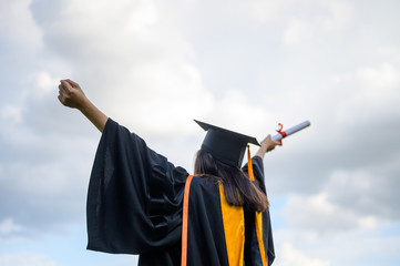 Long haired female students wearing black ruffle dresses expressing joy on graduation at the...