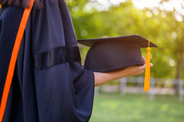 Long haired female students wearing black ruffle dresses expressing joy on graduation at the...