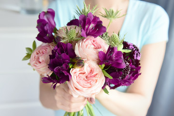Beautiful unusual wedding bouquet of roses, alstromeria, succulents and thorns. Flowers in women's hands close-up.
