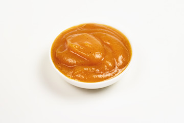 Orange sauce in white plate on white background.