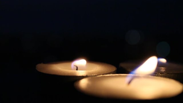 Burning candles in the dark, candlelight with black background, glowing tealight candles