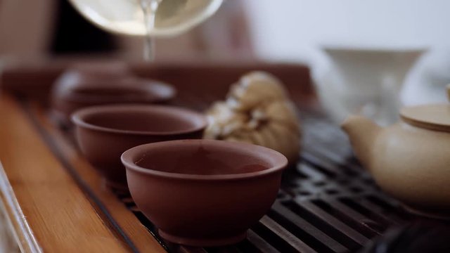 Chinese tea ceremony, on the table is three cups, they poured from a kettle puer. Close-up