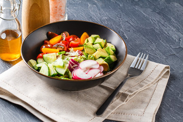 Vegan buddha bowl. Healthy vegetarian salad with cherry tomatoes, cucumber, radish,, avocado and lettuce.