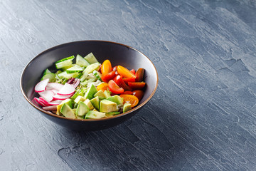 Vegan buddha bowl. Healthy vegetarian salad with cherry tomatoes, cucumber, radish,, avocado and lettuce.