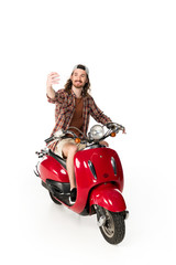 Obraz na płótnie Canvas full length view of young man sitting on red scooter and taking selfie isolated on white