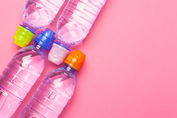 Plastic bottles with pure water on pink background top view space for text