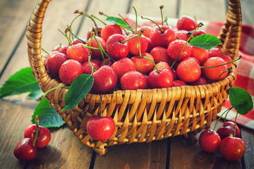 Fototapeta na wymiar Fresh sweet ripe cherries in a basket on the old wooden background