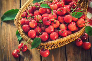 Fresh sweet ripe cherries in a basket on the old wooden background