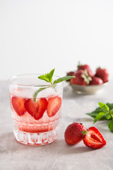 strawberry lemonade with ice and mint in glass on white background. Cold detox water as summer refreshing drink. Copy space