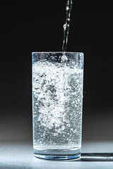 Close up pouring purified fresh drink water from the bottle on table