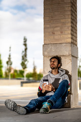 Young Man Sitting And Sending a Message In A Urban Scene