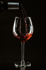 Red wine being poured in a wine glass on a dark background