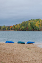 Three boats on the sandy bank of the river. Lush forest in the background