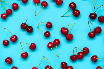 Red ripe cherry beries on blue background. Cherry pattern. Flat lay. Healthy food concept.