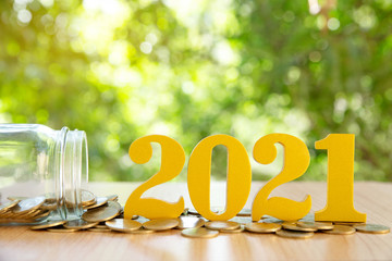 Word 2021 put on coins and glass bottles with coins inside on green bokeh background.Savings New...
