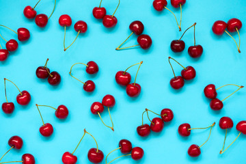 Obraz na płótnie Canvas Red ripe cherry beries on blue background. Cherry pattern. Flat lay. Healthy food concept.