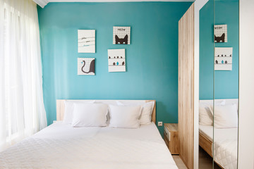 Hotel bedroom with blue walls, white curtains, pillowcases and sheets